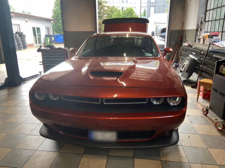 Pomarańczowy Dodge Challenger widziany od przodu w warsztacie